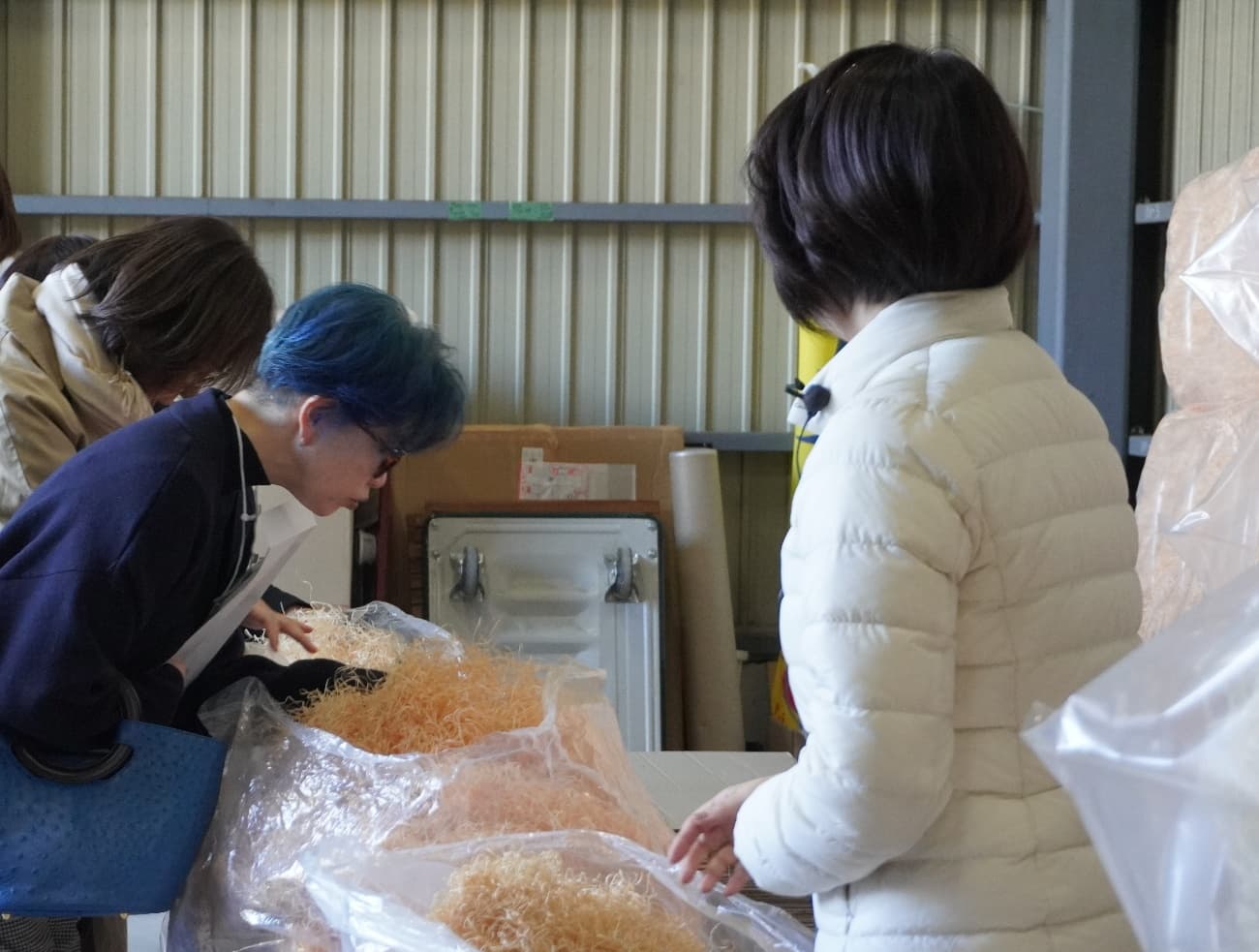 倉庫内で袋詰めされたもくめんを参加者が眺めている様子