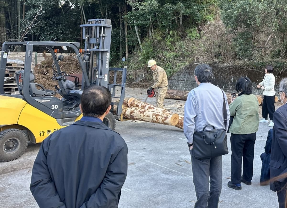フォークリフトと丸太を使い、製材工程について実演説明を行っている様子