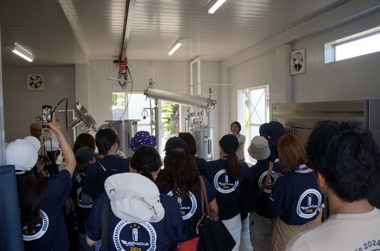 エッセンシャルオイルの蒸留施設の前で参加者が見学している様子